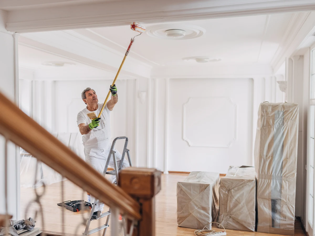 Professional ceiling painter using roller on white ceiling in Beaconsfield