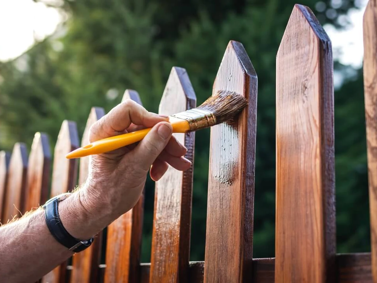 fence-painting-hand-wooden-picket Hands working on picket fence painting, close-up detail of brush technique in Beaconsfield
