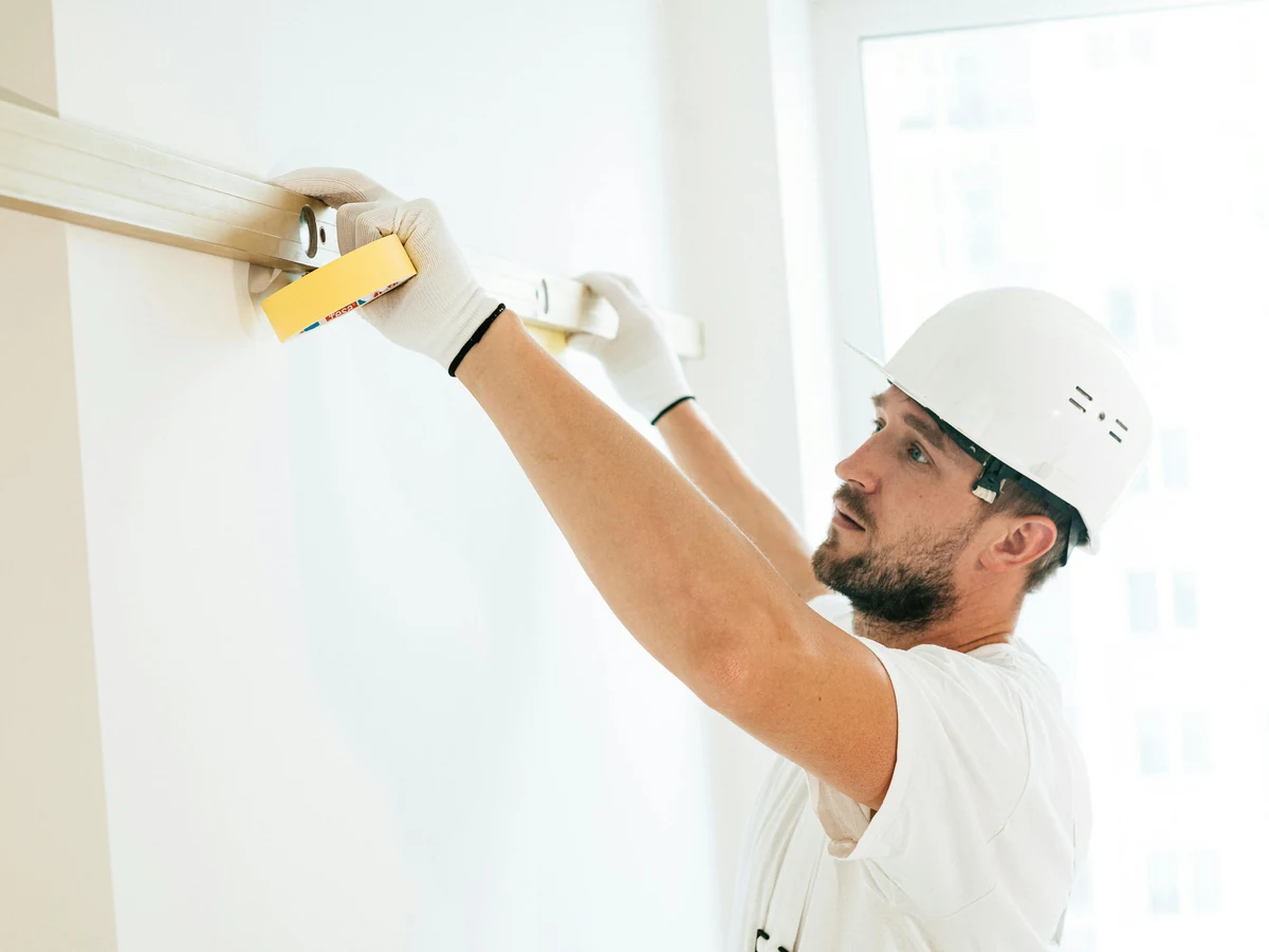 Professional decorator sanding ceiling surface in preparation for painting